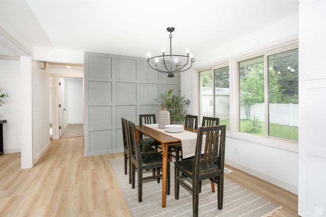 Dining area with a chandelier, light wood-type flooring, baseboards, and a decorative wall | Image 17