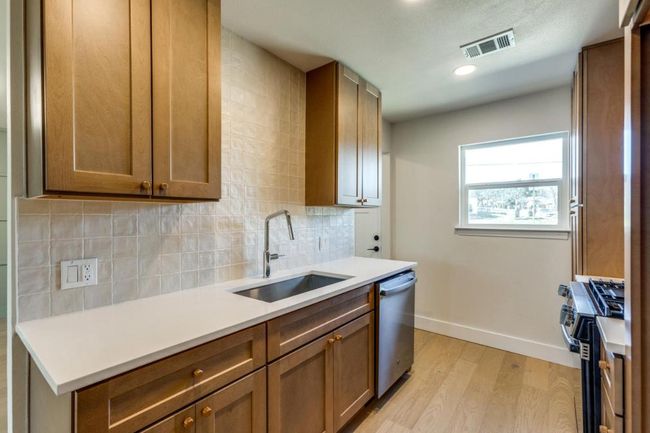 Kitchen with light wood finished floors, visible vents, a sink, stainless steel appliances, and backsplash | Image 17