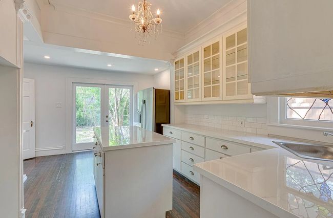 Kitchen with stainless steel fridge, a kitchen island, a chandelier, dark wood finished floors, and crown molding | Image 7