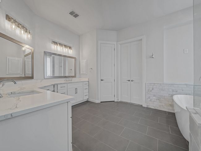 Bathroom with double vanity, a freestanding bath, tile patterned flooring, tile walls, and a wainscoted wall | Image 12
