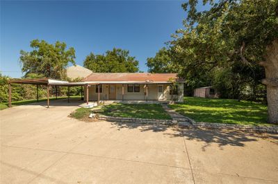 View of front facade featuring a front yard, a carport, and a porch | Image 2