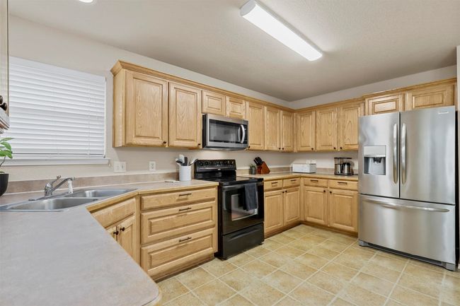 Kitchen with light tile patterned floors, stainless steel appliances, a sink, light countertops, and light brown cabinetry | Image 16