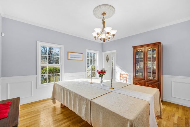Dining room with crown molding and wainscoting offers a formal space for holiday entertaining. | Image 7