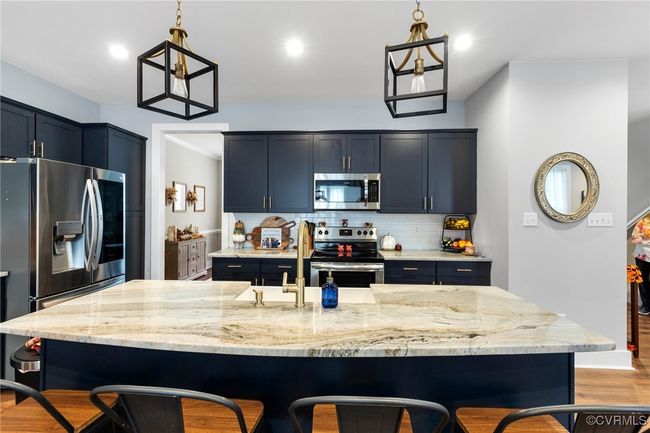 Kitchen featuring a breakfast bar area, backsplash, a sink, light stone counters, and stainless steel appliances | Image 14