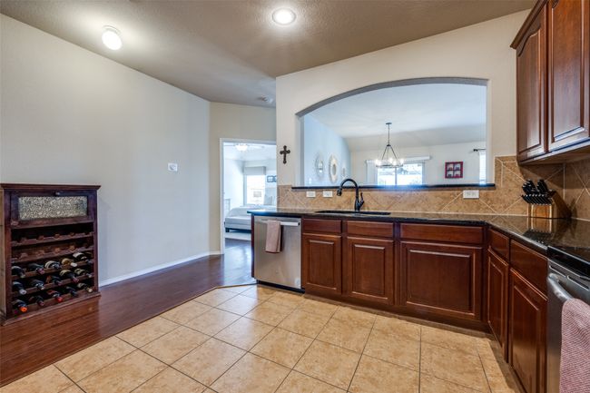 Kitchen with stainless steel dishwasher, decorative backsplash, stove, arched walkways, and light tile patterned floors | Image 13
