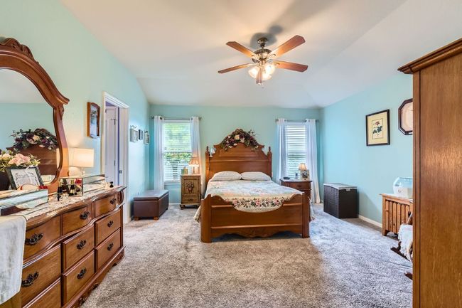 Bedroom featuring lofted ceiling, light carpet, a ceiling fan, and baseboards | Image 13