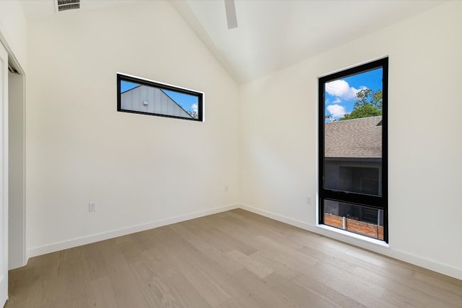 Empty room featuring light wood-style floors and high vaulted ceiling | Image 21