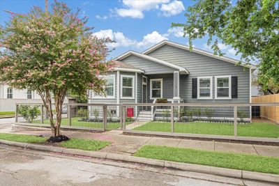 This stunning gray craftsman-style home boasts a welcoming front porch and lush landscaping. | Image 1