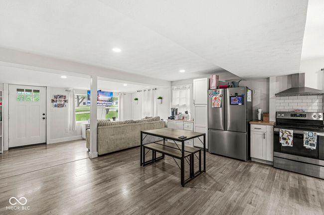 kitchen with stainless steel appliances, wall chimney exhaust hood, wood finished floors, recessed lighting, and open floor plan | Image 8