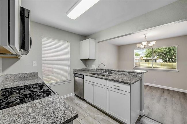 Kitchen featuring a sink, stainless steel dishwasher, a peninsula, and white cabinets | Image 8