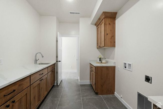 Clothes washing area featuring a sink, dark tile patterned flooring, hookup for an electric dryer, visible vents, and washer hookup | Image 22