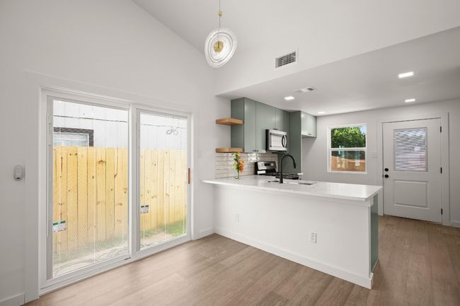 Kitchen featuring stainless steel microwave, light countertops, open shelves, a peninsula | Image 25