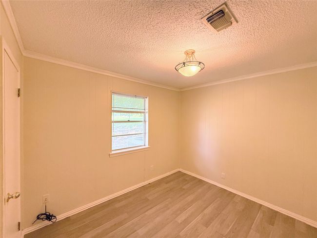 Spare room with light wood-style flooring, a textured ceiling, and crown molding | Image 20