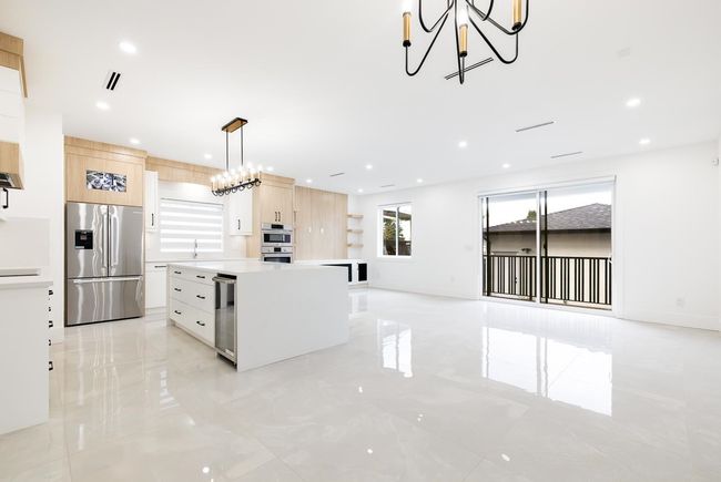 Kitchen featuring stainless steel appliances, light brown cabinetry, modern cabinets, beverage cooler, and a chandelier | Image 13