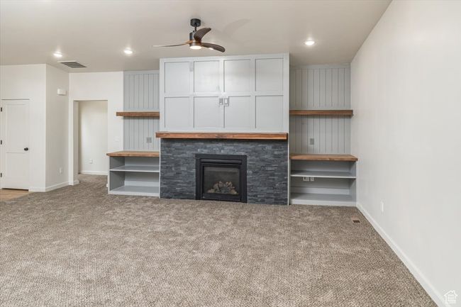 Unfurnished living room with a fireplace, light colored carpet, and ceiling fan | Image 5