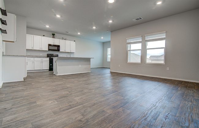 Kitchen featuring visible vents, dark wood-style flooring, open floor plan, white cabinetry, and black appliances | Image 10