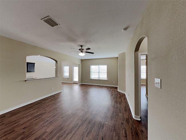 Empty room featuring ceiling fan, dark wood-style floors, arched walkways, and a textured wall | Image 8