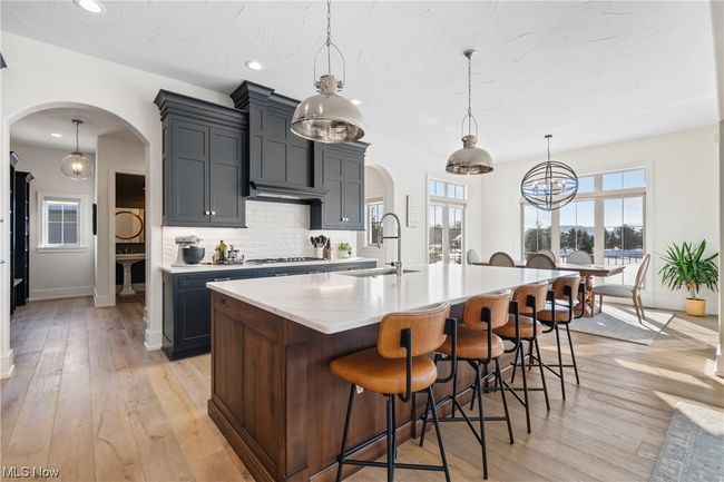 Kitchen with a kitchen island with sink, light hardwood / wood-style flooring, and decorative light fixtures | Image 10