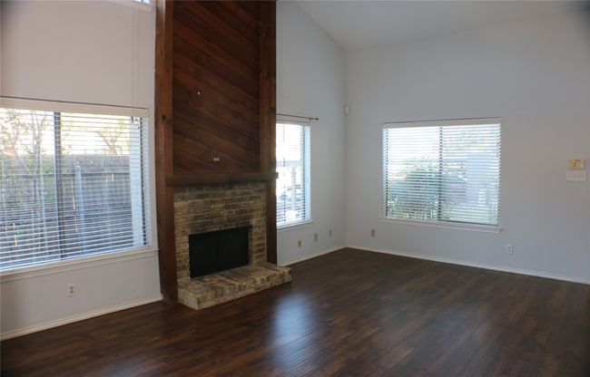 Unfurnished living room featuring wood finished floors, a fireplace, and vaulted ceiling | Image 15