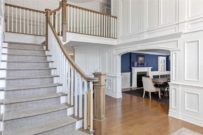 Stairway with a decorative wall, wood finished floors, arched walkways, a towering ceiling, and a fireplace | Image 5