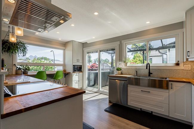 Kitchen featuring wood counters, appliances with stainless steel finishes, extractor fan, a sink, and healthy amount of natural light | Image 8