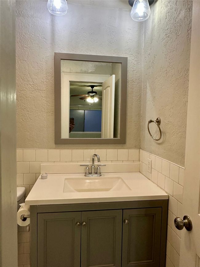Full bathroom featuring a textured wall, vanity, tile walls, wainscoting, and a ceiling fan | Image 24