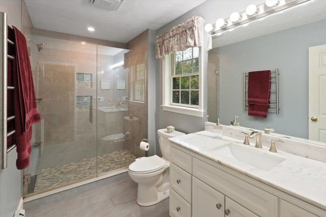 Beautifully updated 3/4 bath featuring a gorgeous marble vanity, tiled floors, and custom-tiled shower. | Image 19