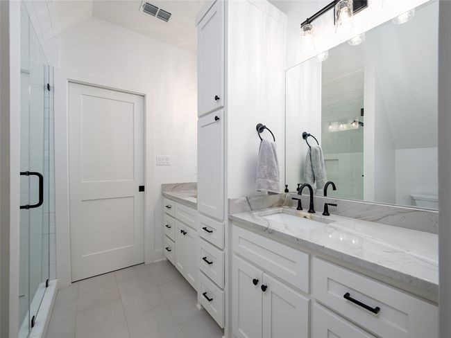 Full bathroom with double vanity, a stall shower, tile patterned flooring, and vaulted ceiling | Image 27