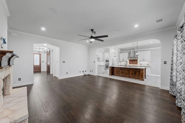 Unfurnished living room featuring a ceiling fan, hardwood / wood-style floors, arched walkways, ornamental molding, and recessed lighting | Image 8