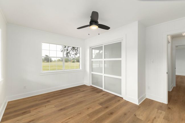Bright and inviting front bedroom with large windows, modern ceiling fan, and sleek sliding closet doors. Enjoy abundant natural light and serene views. | Image 30