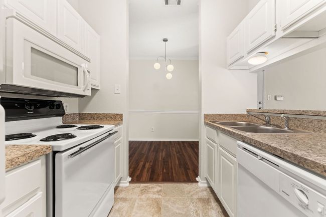 Kitchen with ornamental molding, white appliances, white cabinetry, and a sink | Image 14