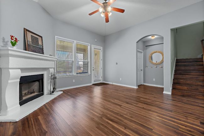 Living room with a ceiling fan, arched walkways, a fireplace with raised hearth, and wood finished floors | Image 15
