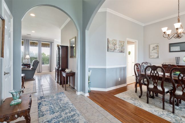 Dining area featuring a chandelier, arched walkways, ornamental molding, light tile patterned floors, and recessed lighting | Image 10