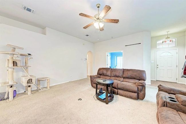 Carpeted living area featuring a ceiling fan and arched walkways | Image 12