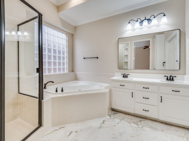 Full bath with a garden tub, crown molding, shower, double vanity with new marble counter and undermount sinks, and marble finish tile flooring. Also includes a large walk in closet and custom linen closet. | Image 17