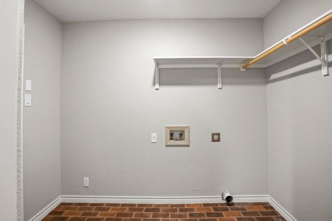 Laundry area an electric dryer, washer included, with brick patterned flooring | Image 24