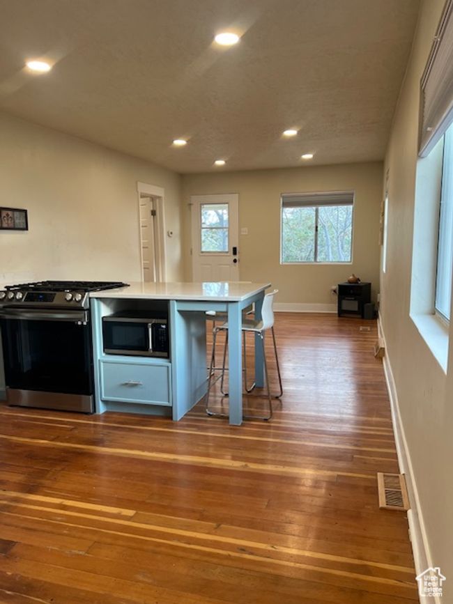 Open kitchen and main living area with stainless steel appliances, recessed lighting, original restored hardwood floors, custom cupboards. | Image 12