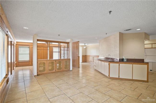 Kitchen featuring a textured ceiling, a wainscoted wall, a ceiling fan, recessed lighting, and light tile patterned floors | Image 4