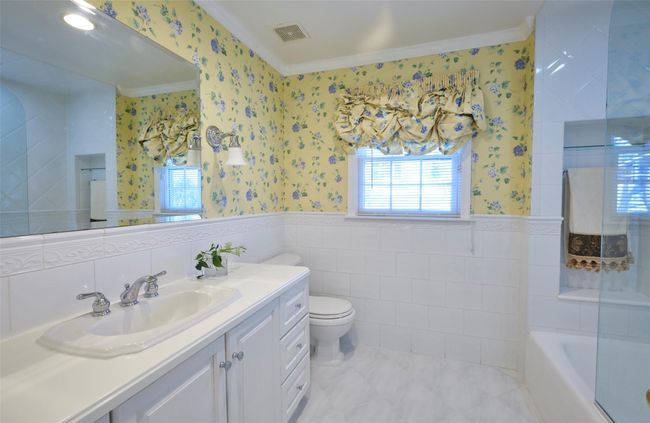 Bathroom with a wainscoted wall, a bath, toilet, and wallpapered walls | Image 13