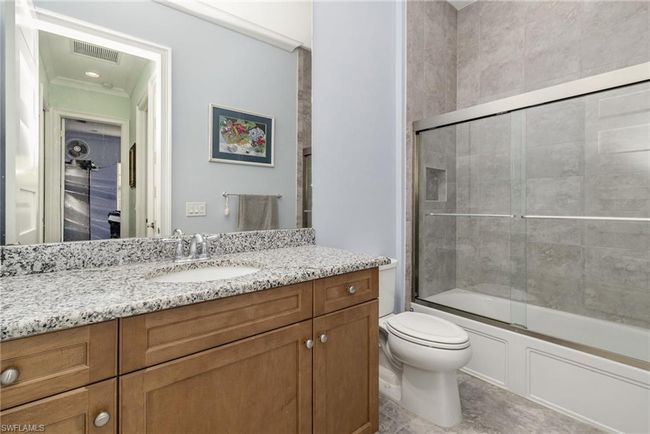 Full bathroom featuring shower / bath combination with glass door, vanity, and toilet | Image 13
