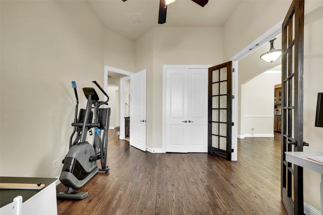Workout area with dark wood-style flooring, arched walkways, and a ceiling fan | Image 32