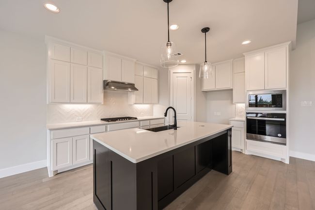 Kitchen featuring oven, gas cooktop, under cabinet range hood, a sink, and built in microwave | Image 10