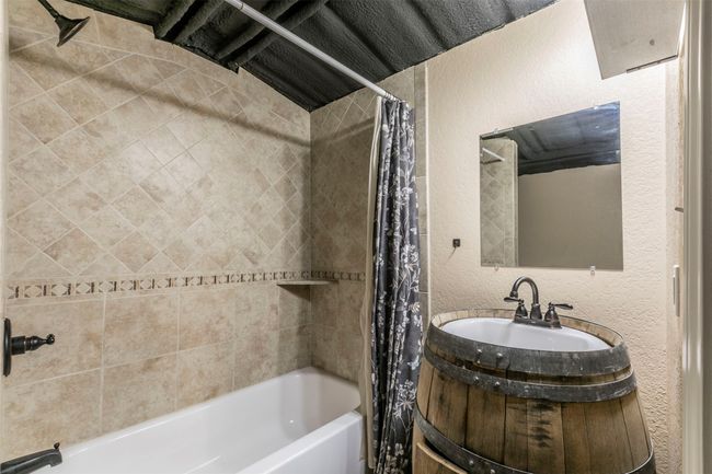 Full bathroom featuring shower / tub combo, a textured wall, and vanity | Image 25