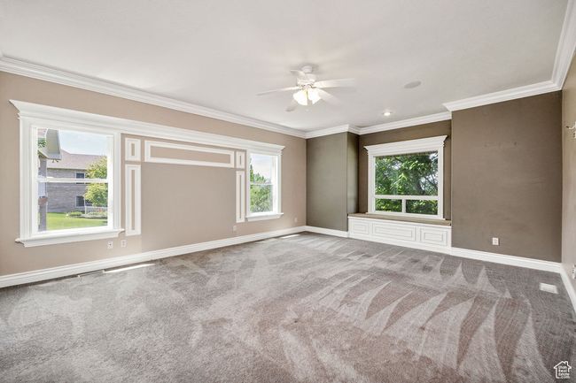 Carpeted empty room with a ceiling fan, baseboards, and ornamental molding | Image 14