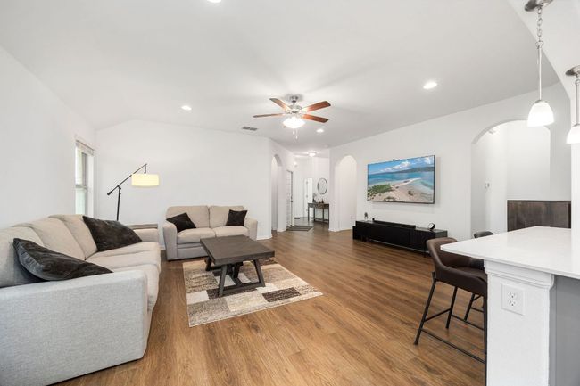 Living area featuring arched walkways, ceiling fan, wood finished floors, and recessed lighting | Image 8
