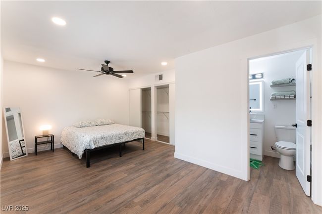 Bedroom featuring connected bathroom, wood finished floors, baseboards, visible vents, and recessed lighting | Image 17
