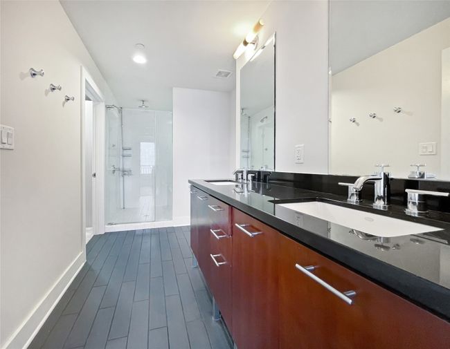 Full bath with a stall shower, baseboards, double vanity, and wood finish floors | Image 17
