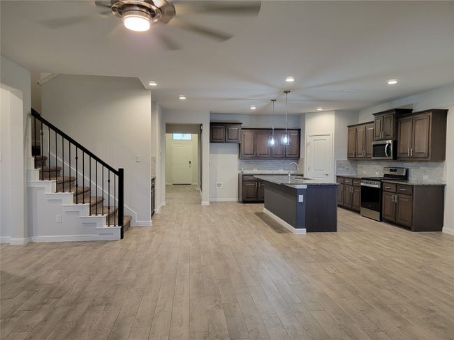 Kitchen with stainless steel appliances, light wood-style flooring, a ceiling fan, dark brown cabinetry, and recessed lighting | Image 6