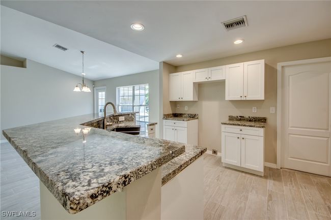 Kitchen featuring stone countertops, light wood-style floors, white cabinets, and a sink | Image 28