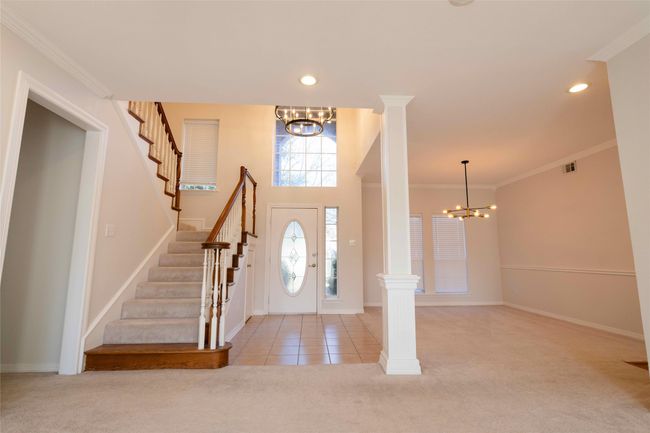 Entryway featuring a chandelier, light carpet, stairway, crown molding, and decorative columns | Image 12